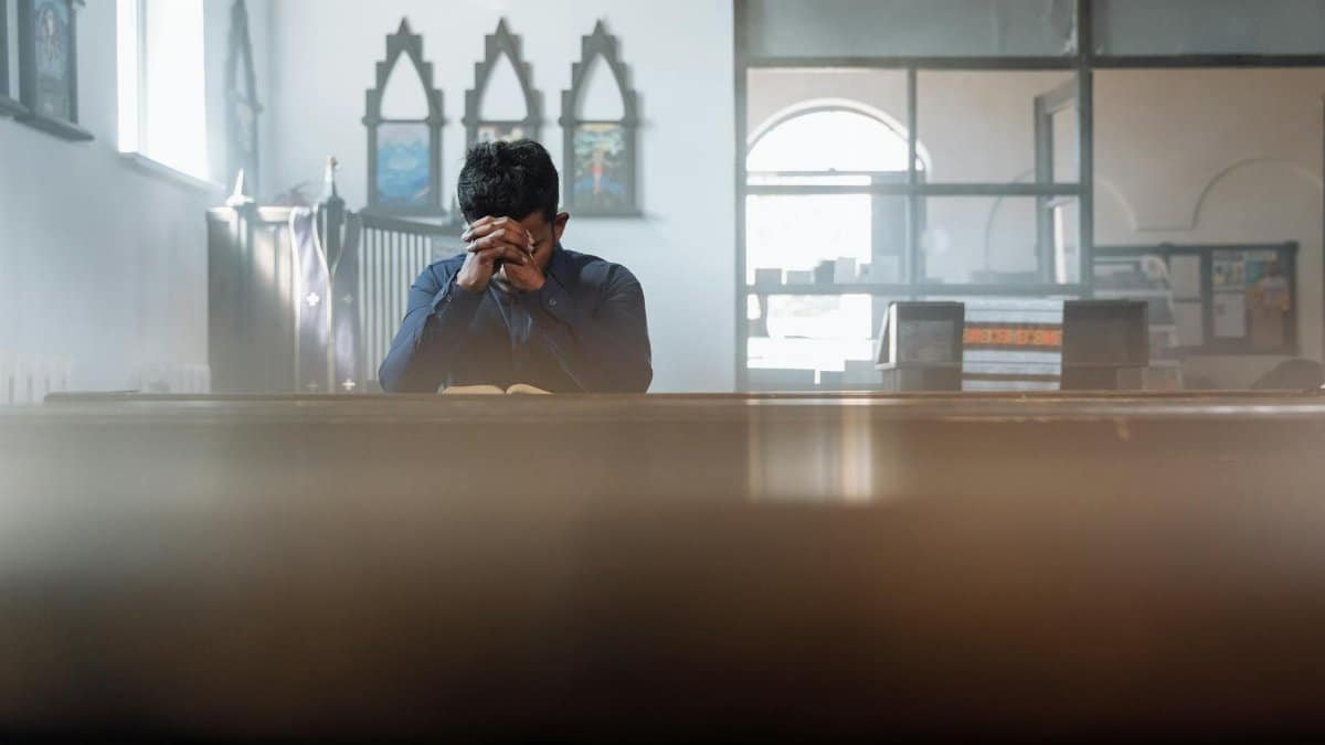 A man in prayer in a sunlit room, reflecting spirituality and peace.