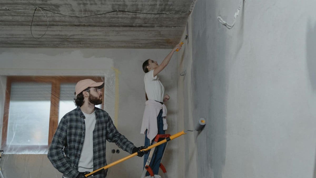 A couple painting a room together, highlighting teamwork in home renovation.