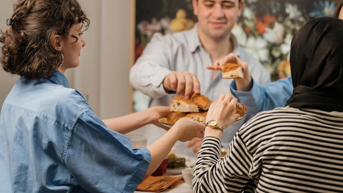 Friends sharing bread and enjoying a meal around a dining table, conveying warmth and togetherness.