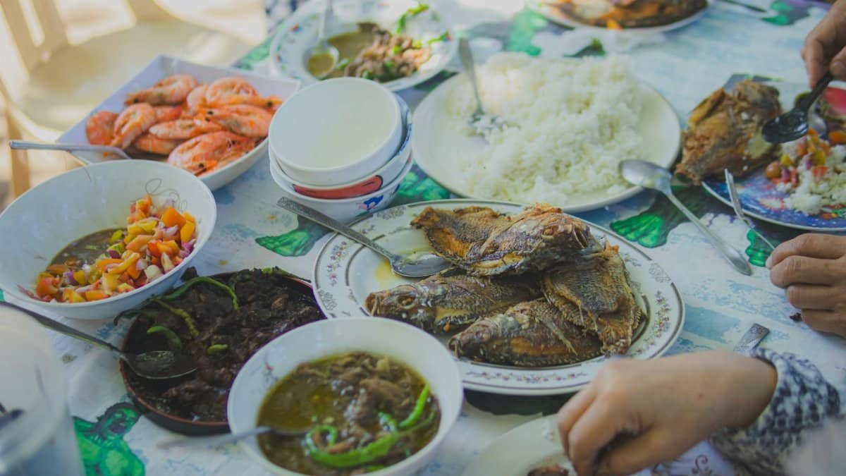 Enjoy a homemade seafood dinner with rice and vibrant side dishes, perfect for shared meals.