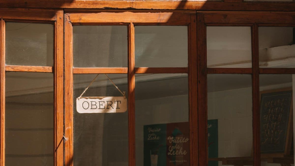 A wooden doorway with an 'OBERT' sign, illuminated by sunlight in Valencia, Spain.
