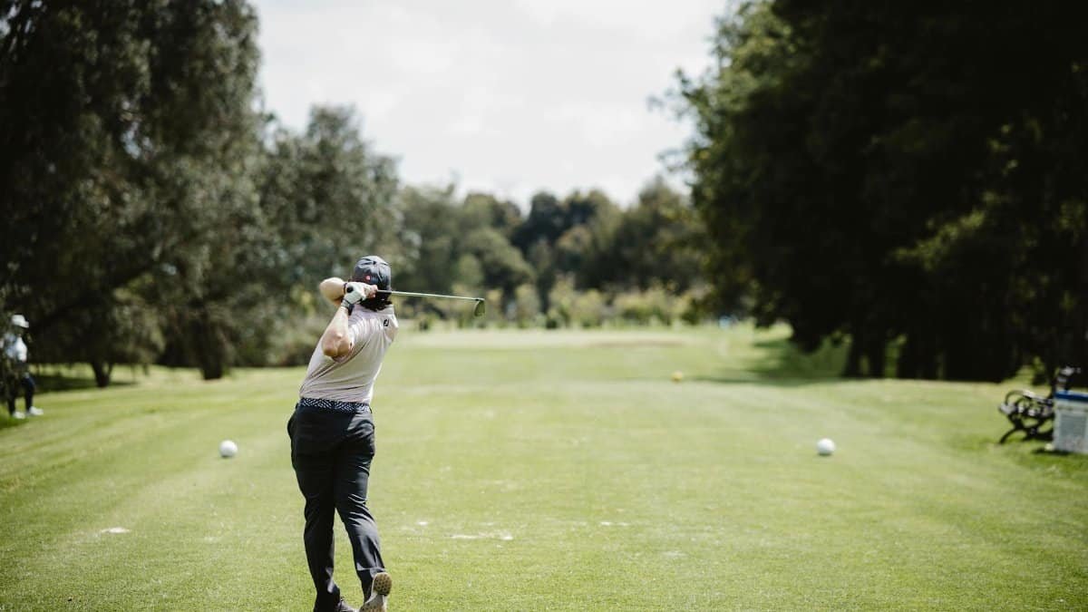 A golfer swings on a bright day in Bogotá, Colombia's lush green golf course.