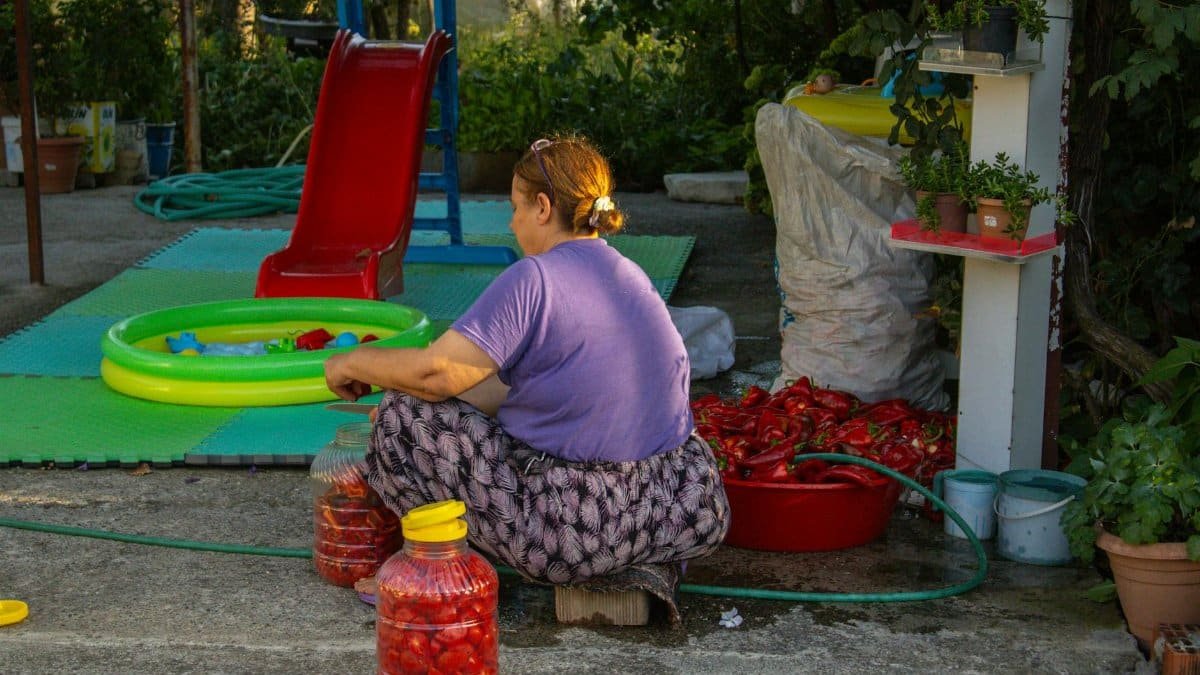 A woman in Türkiye prepares peppers outdoors, showcasing local culinary traditions.