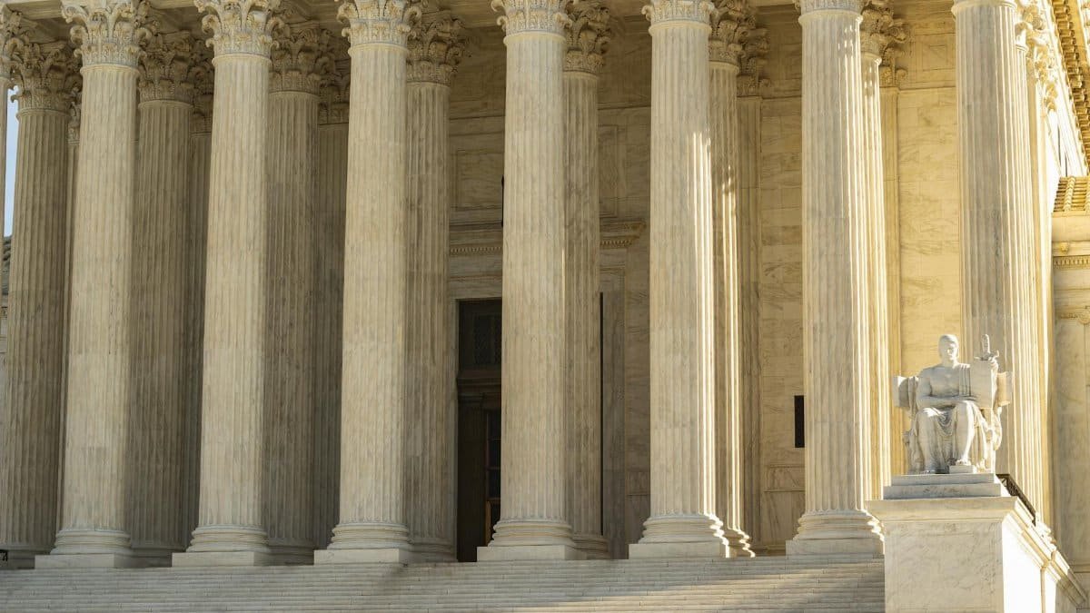 The Supreme Court of the United States with iconic marble columns and statue, captured in natural light.