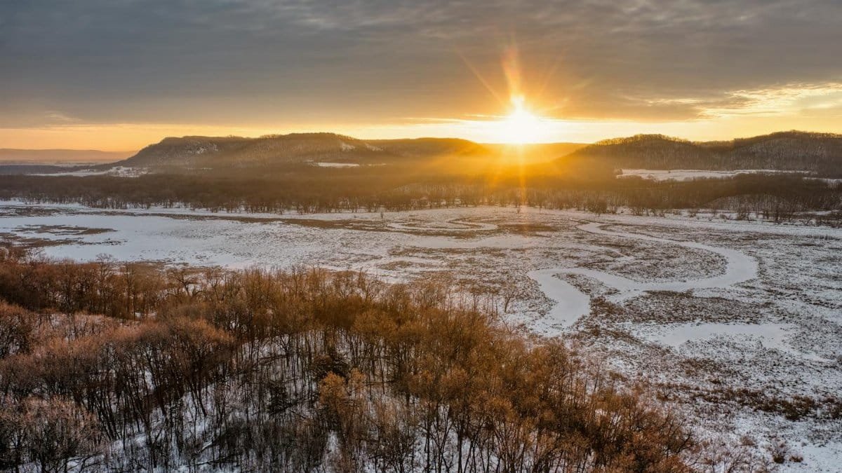 A breathtaking sunrise over a snowy valley and forest in Weaver, Minnesota, USA.