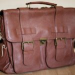 Stylish brown leather satchel on wooden flooring, perfect for travel or business.