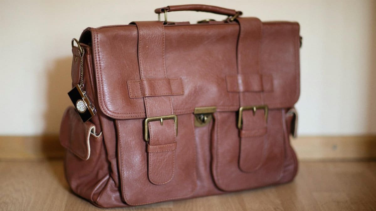 Stylish brown leather satchel on wooden flooring, perfect for travel or business.