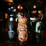 Vibrant tiki cocktails with bokeh lights in a cozy bar. Perfect for festive gatherings and exotic drinks.