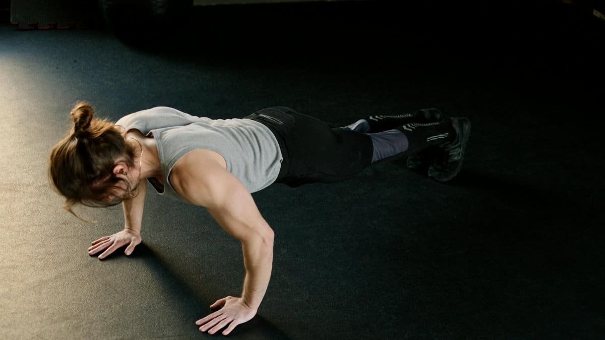 Adult male performing push-ups on gym floor, showcasing fitness and strength.