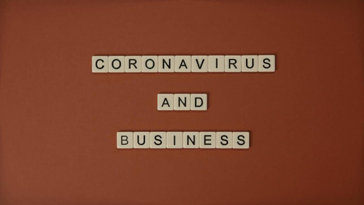 Scrabble tiles spelling 'Coronavirus and Business' on an orange background, illustrating pandemic impact.