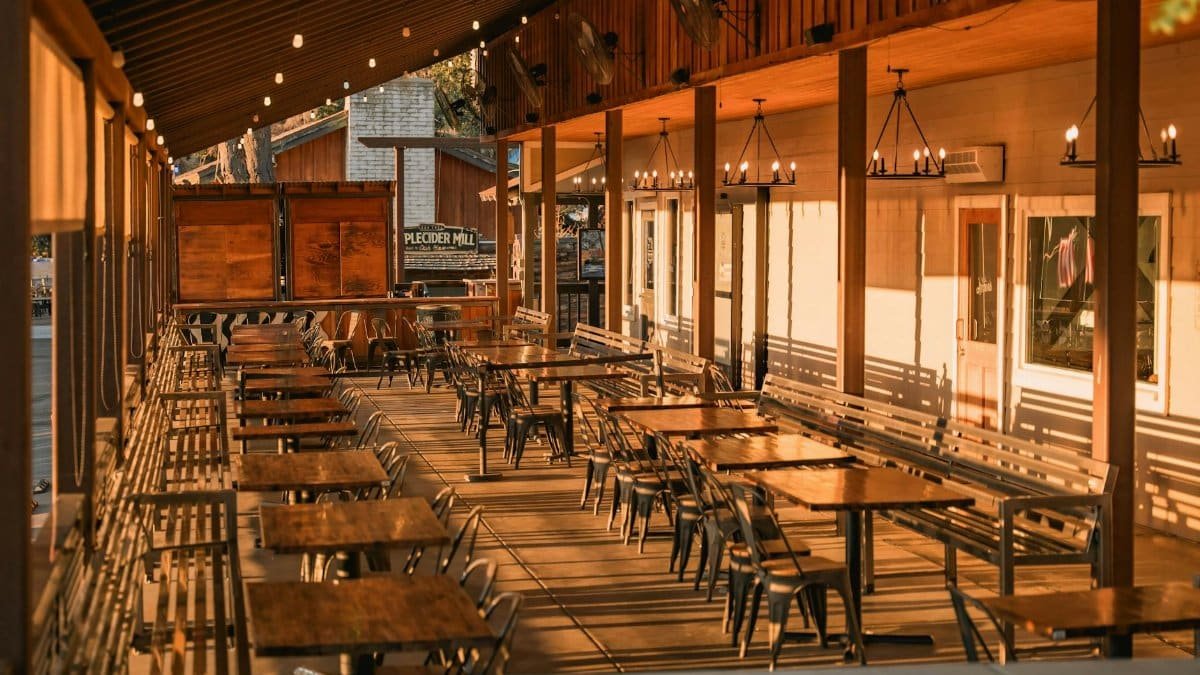 Warm and inviting outdoor patio area with wooden tables, chairs, and ambient lighting, perfect for dining.