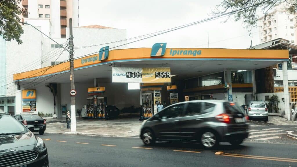 Ipiranga gas station with moving vehicles on a bustling city street.