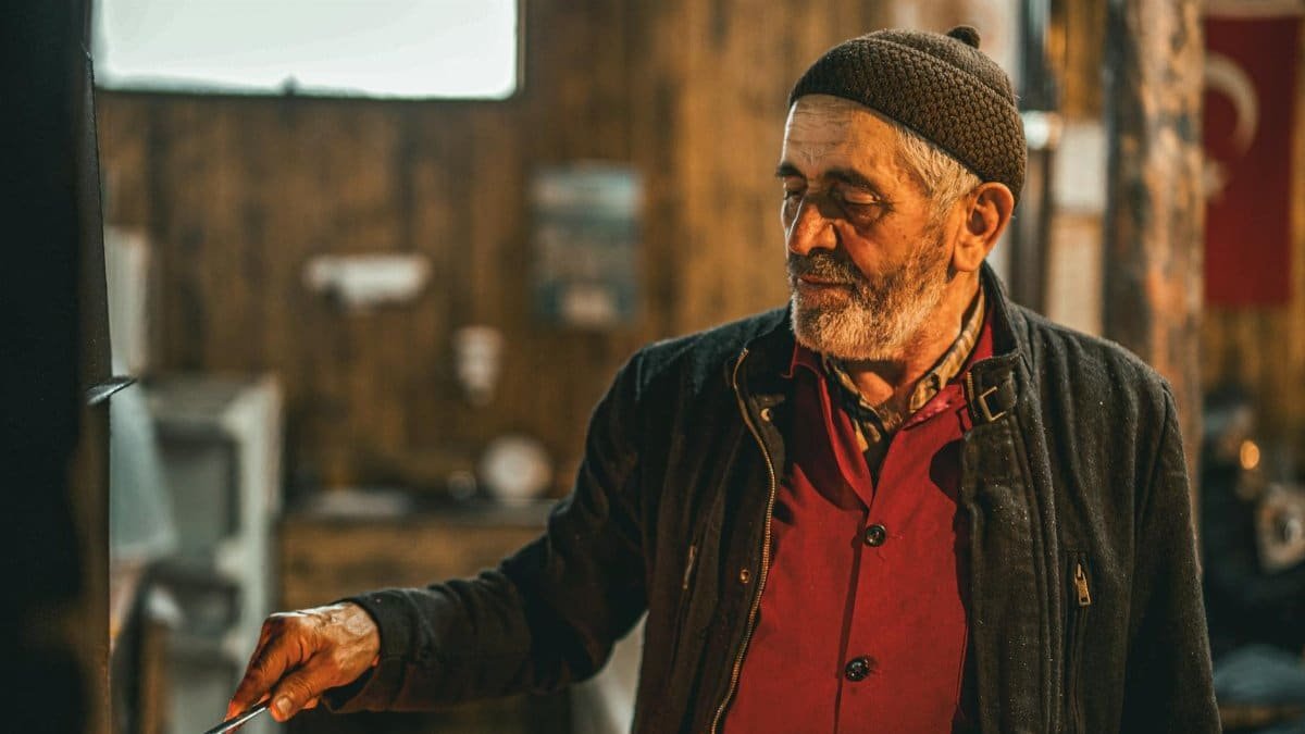 Elderly man in rustic setting with warm lighting, portraying heritage and wisdom.