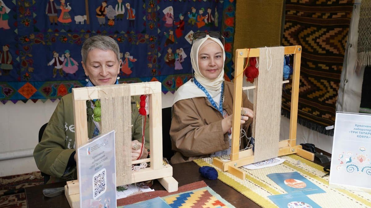 Two women engaging in traditional textile weaving at an arts and crafts workshop, demonstrating cultural heritage.