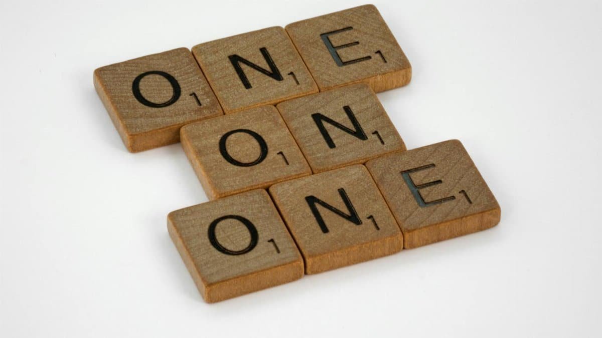 Scrabble letter tiles arranged to spell 'ONE' in a crossword style on a white background.