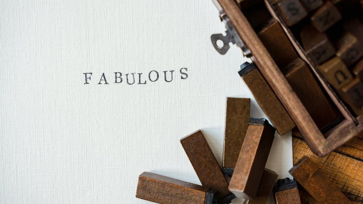 Close-up of wooden letter stamps with 'Fabulous' text on paper, artistic flatlay.