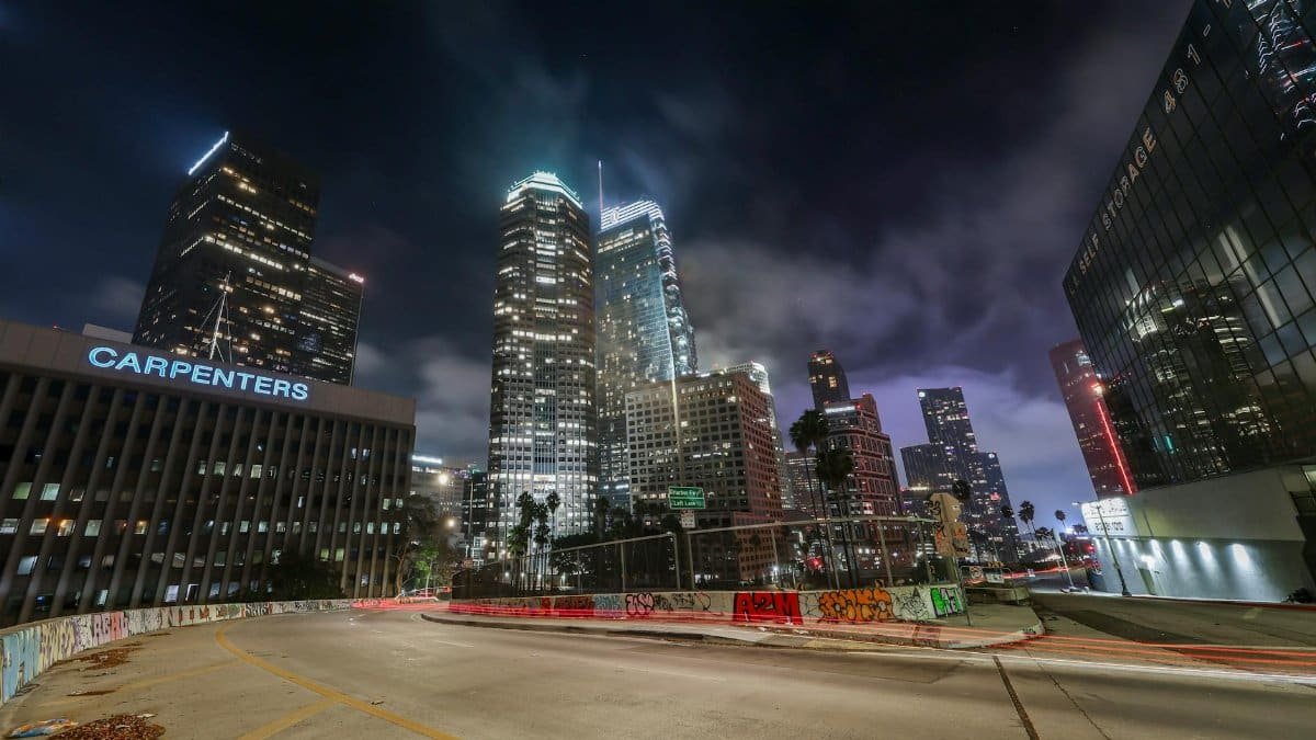 Vibrant night view of downtown Los Angeles with illuminated skyscrapers and light trails.