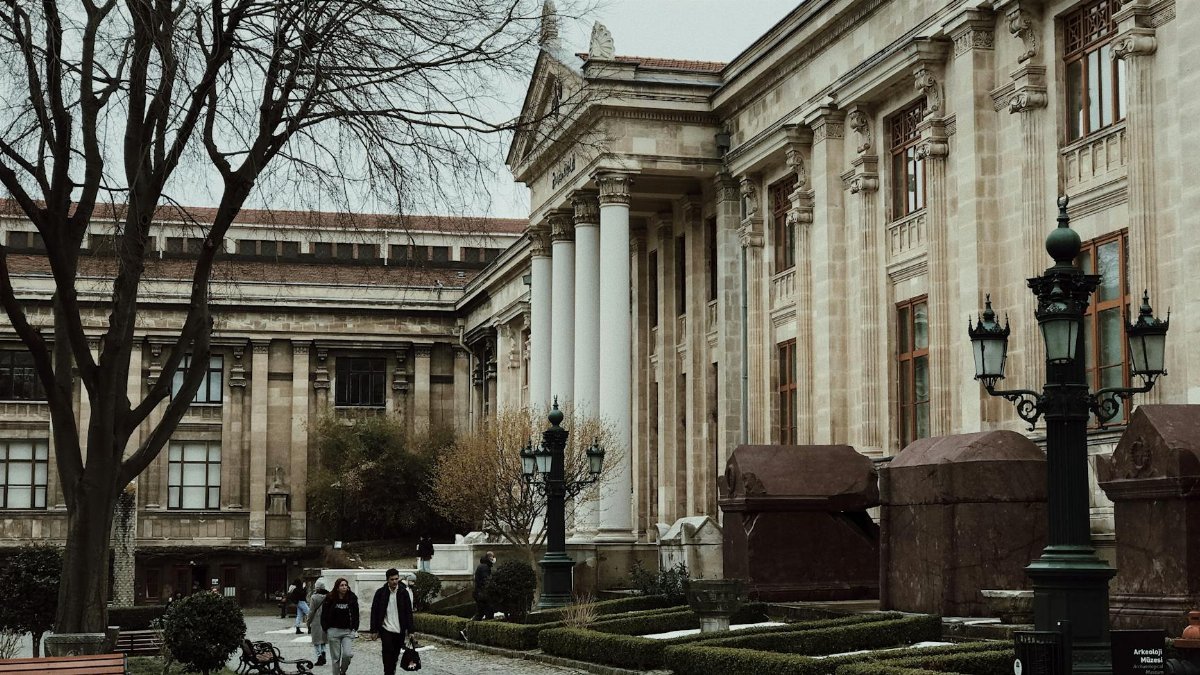 Exterior view of the Istanbul Archaeological Museums with visitors walking along a cobblestone path.