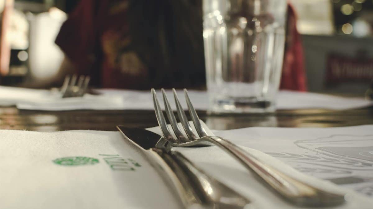 Close-up of a neat table setting with silverware and a glass in an indoor dining environment.