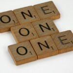 Scrabble letter tiles arranged to spell 'ONE' in a crossword style on a white background.