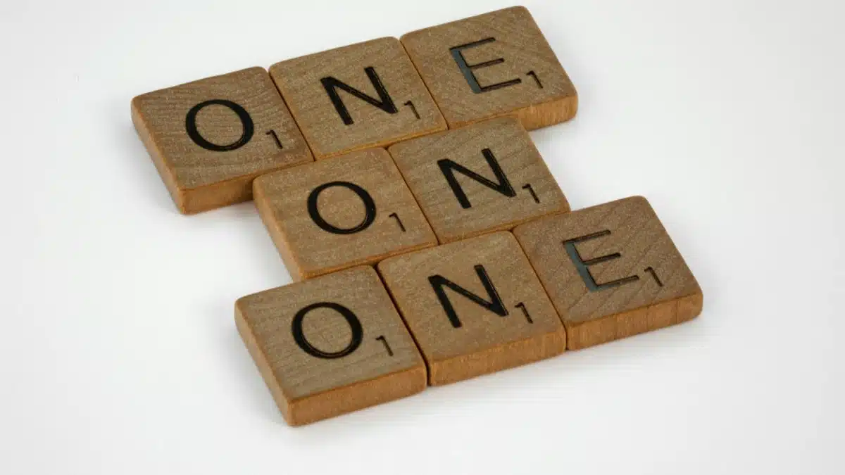 Scrabble letter tiles arranged to spell 'ONE' in a crossword style on a white background.