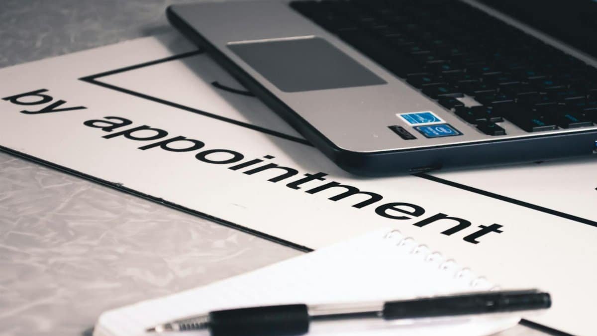 Close-up view of a modern workspace featuring a laptop, notepad, and pen on a desk.