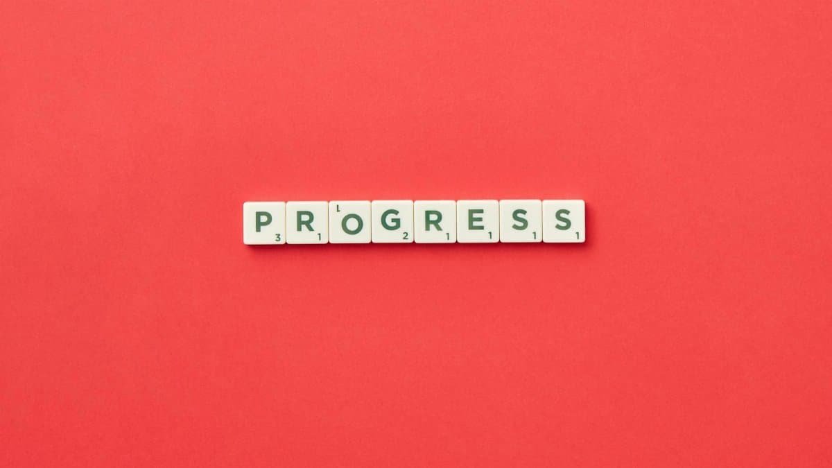 Scrabble tiles spelling 'Progress' on a vibrant red background, symbolizing development.