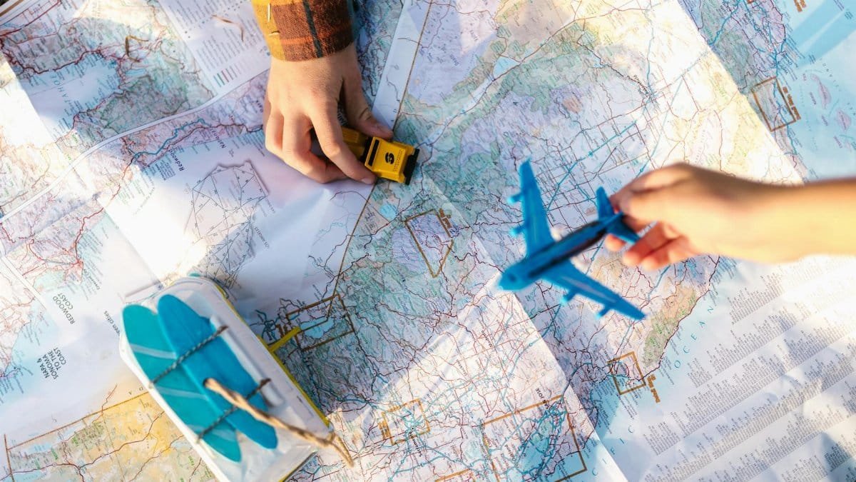 Hands holding a toy airplane and car over a map, symbolizing travel planning and exploration.