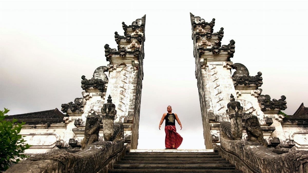 A man stands at the historic Pura Lempuyang Luhur Temple in Bali, showcasing traditional culture and architecture.