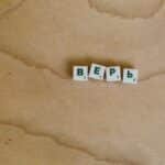 Scrabble tiles with Cyrillic letters spelling 'верь' displayed on a wooden surface.