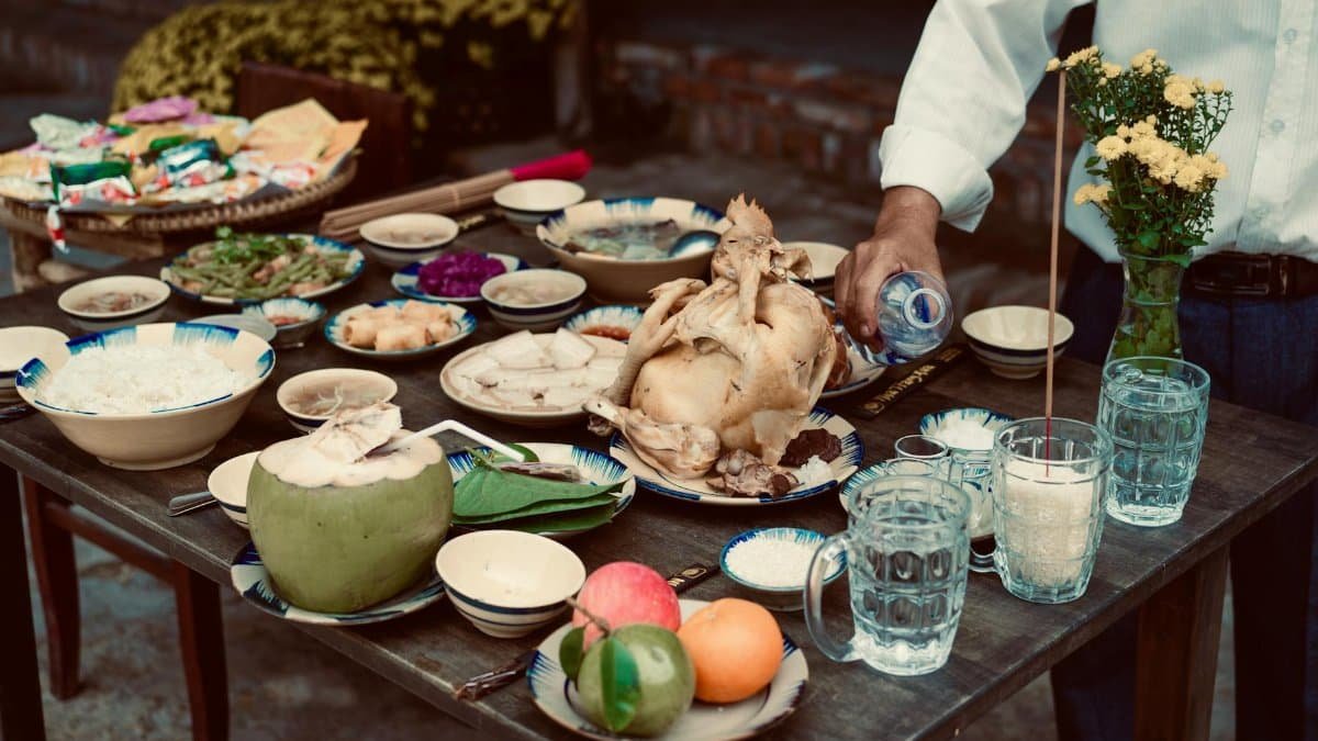 A Vietnamese feast outdoors with chicken, rice, fruits, and drinks. Cultural dining experience.