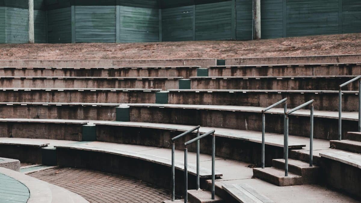 Empty stone steps with seats surrounded with fence placed under sky in public park