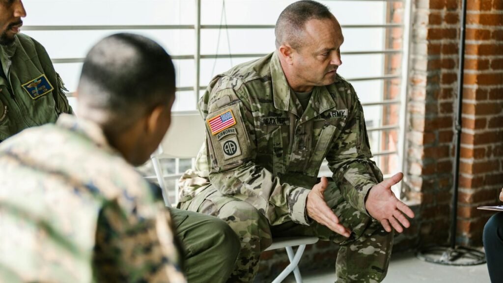 Military veterans engaging in a supportive group therapy session indoors.