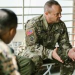 Military veterans engaging in a supportive group therapy session indoors.