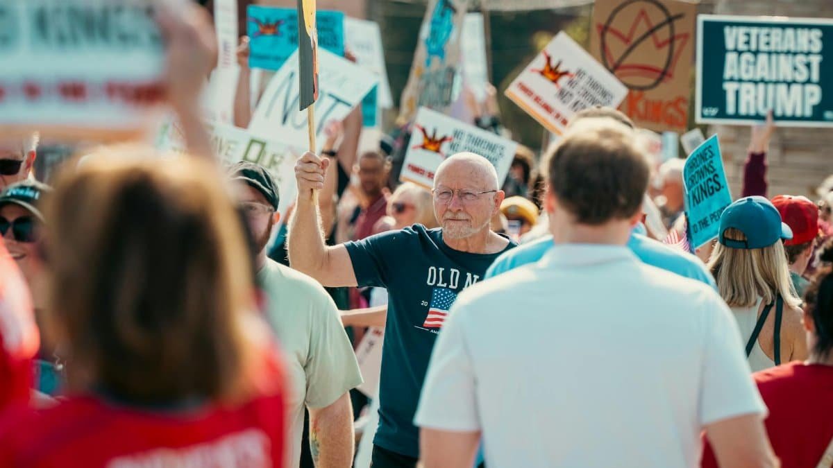 A diverse crowd holding protest signs for a political demonstration outdoors.