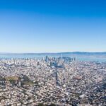 Stunning aerial shot of San Francisco's skyline under a clear blue sky with the Bay in the background.
