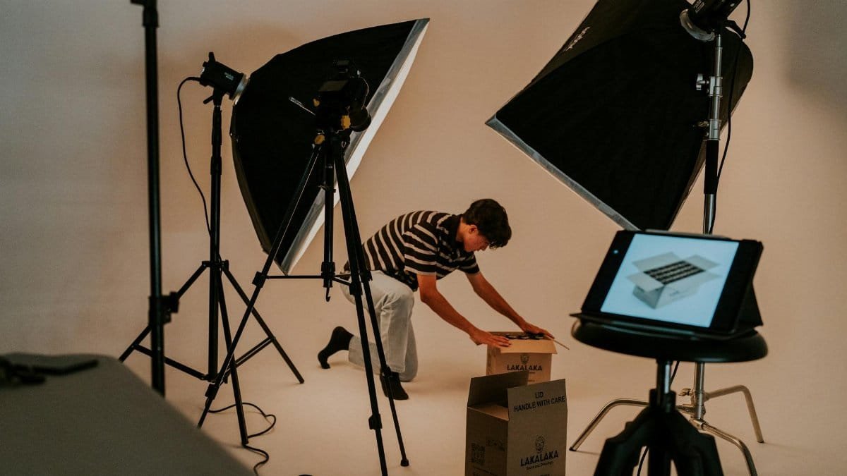 A professional studio scene with a man preparing packages under studio lighting, showcasing a modern photography setup.