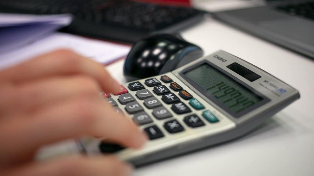 Close-up of a hand using a calculator on an office desk for accurate calculations.