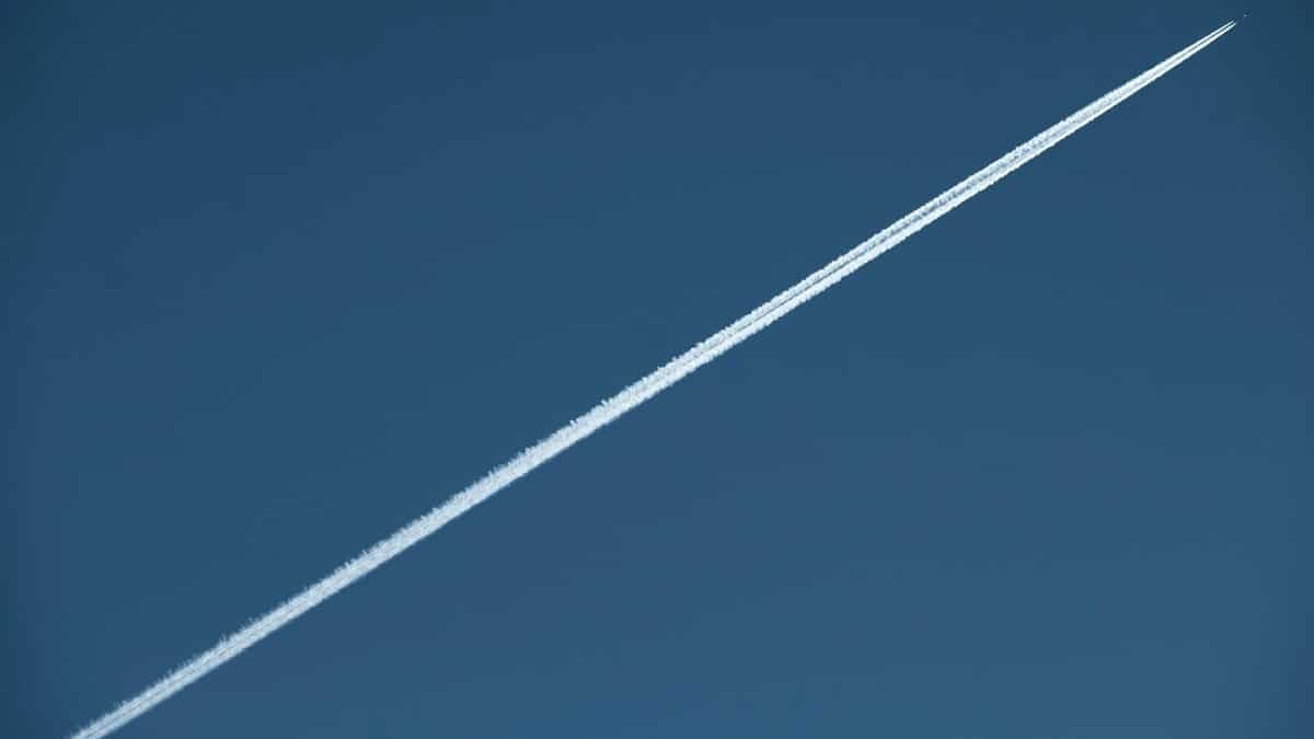 A high-speed jet leaves a distinct contrail in a clear blue sky, showcasing aviation marvel.