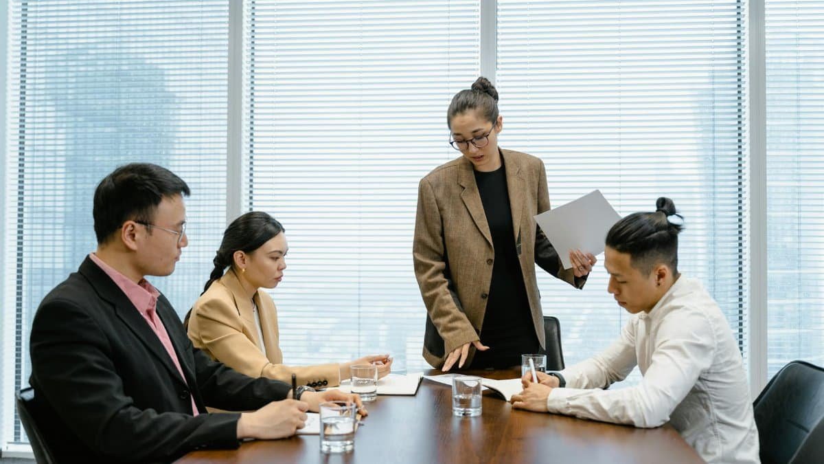 Business colleagues engaged in a meeting around a wooden table within a modern office.