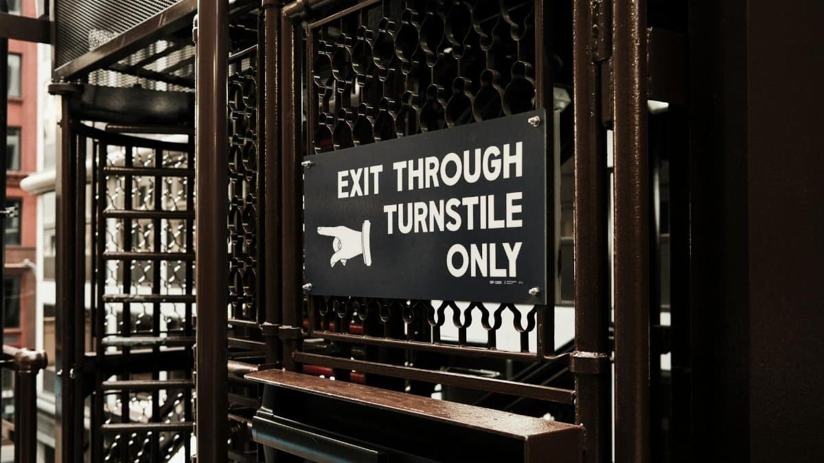 Metal exit sign in Chicago train station indicates turnstile exit only.