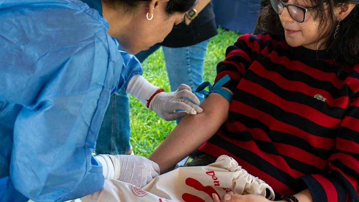 A donor giving blood at an outdoor donation event in Piura, Peru.