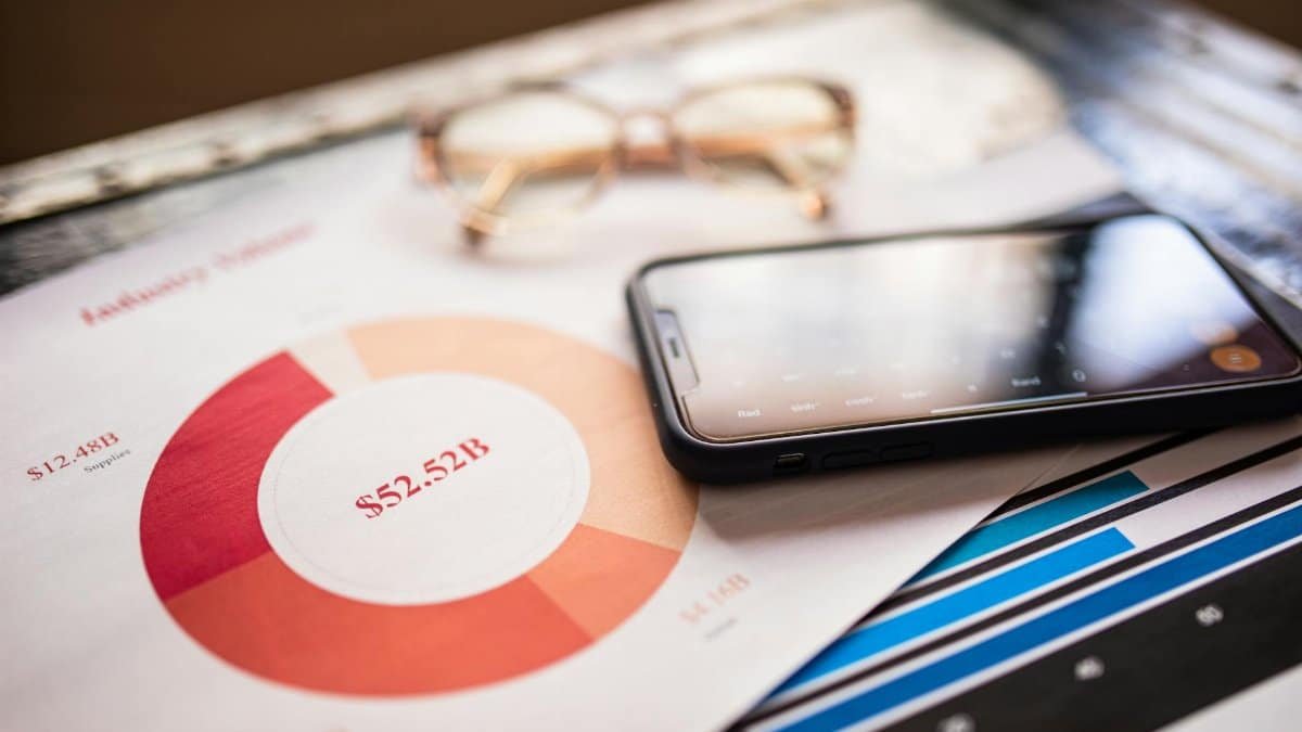 A mobile phone over business charts displaying financial data for analysis.
