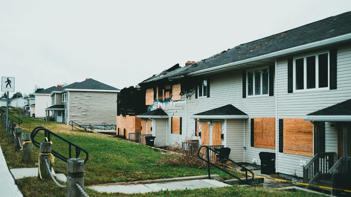 Boarded-up suburban homes with visible fire damage and neglect.