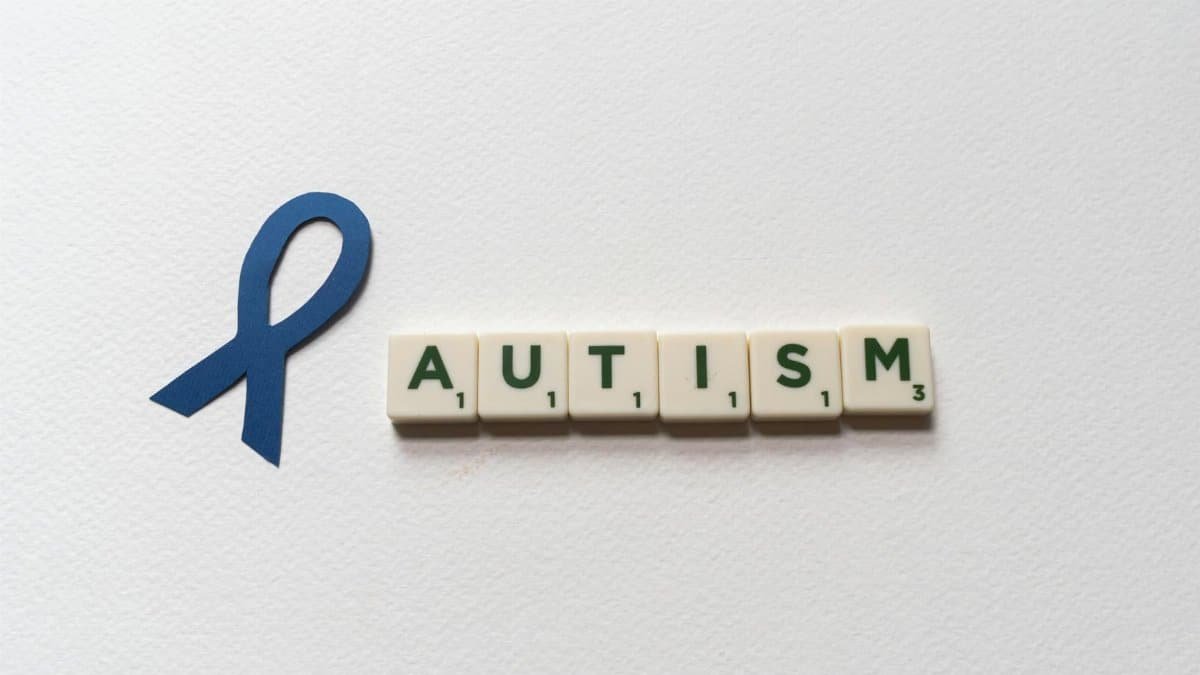 Blue ribbon and autism spelled with letter tiles symbolize autism awareness.