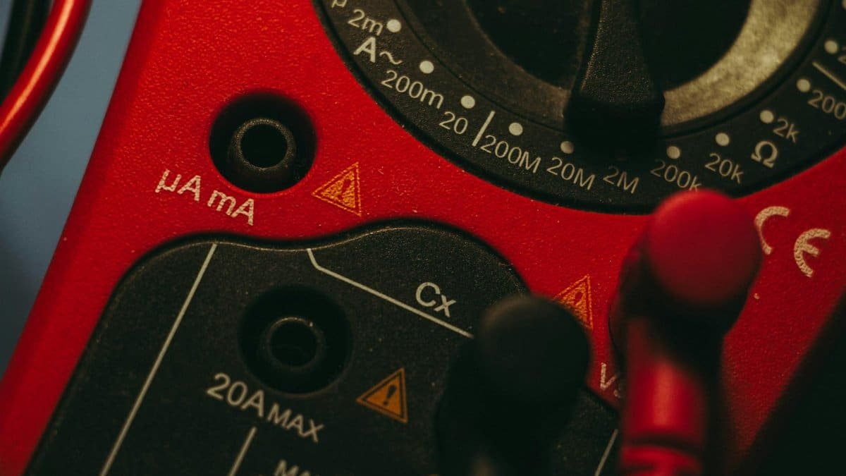 Detailed image of a red multimeter, showcasing measurement dial and connectors, ideal for tech enthusiasts.