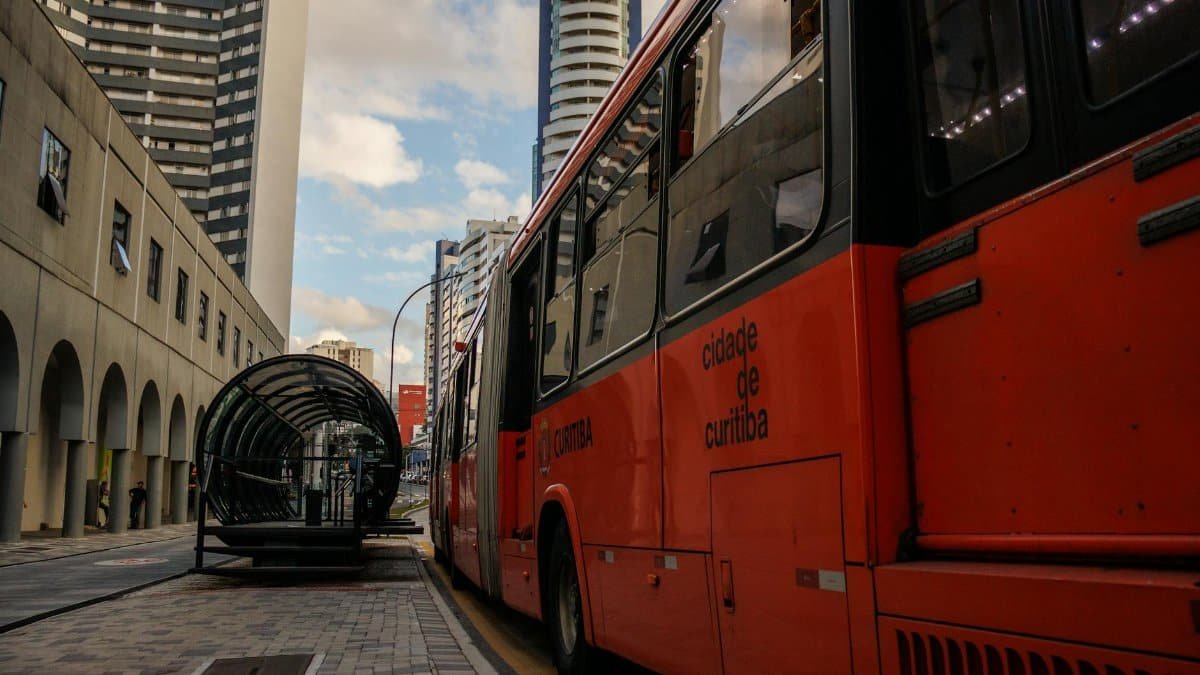 Red city bus at a modern stop in downtown Curitiba, showcasing urban transport.