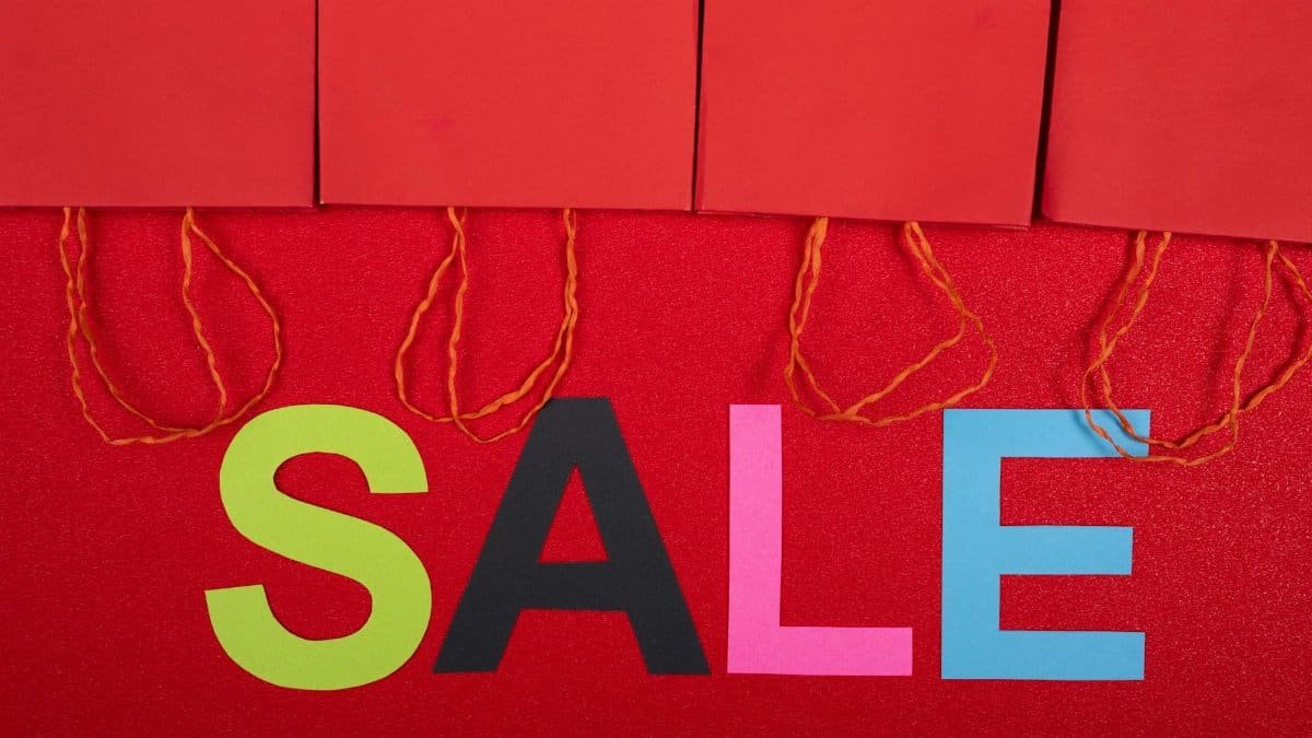 Colorful sale sign with red shopping bags for retail promotions.