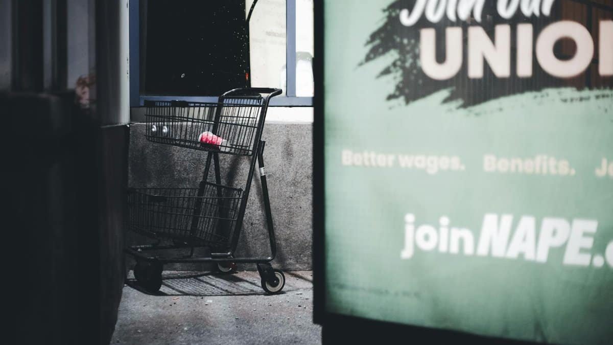 Dramatic urban scene featuring an empty shopping cart and a union sign at night.