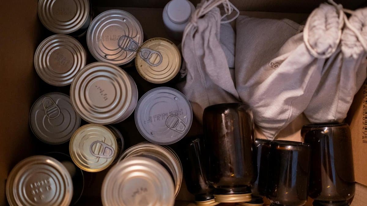 Top view of a box filled with canned goods, jars, and cloth sacks for storage.